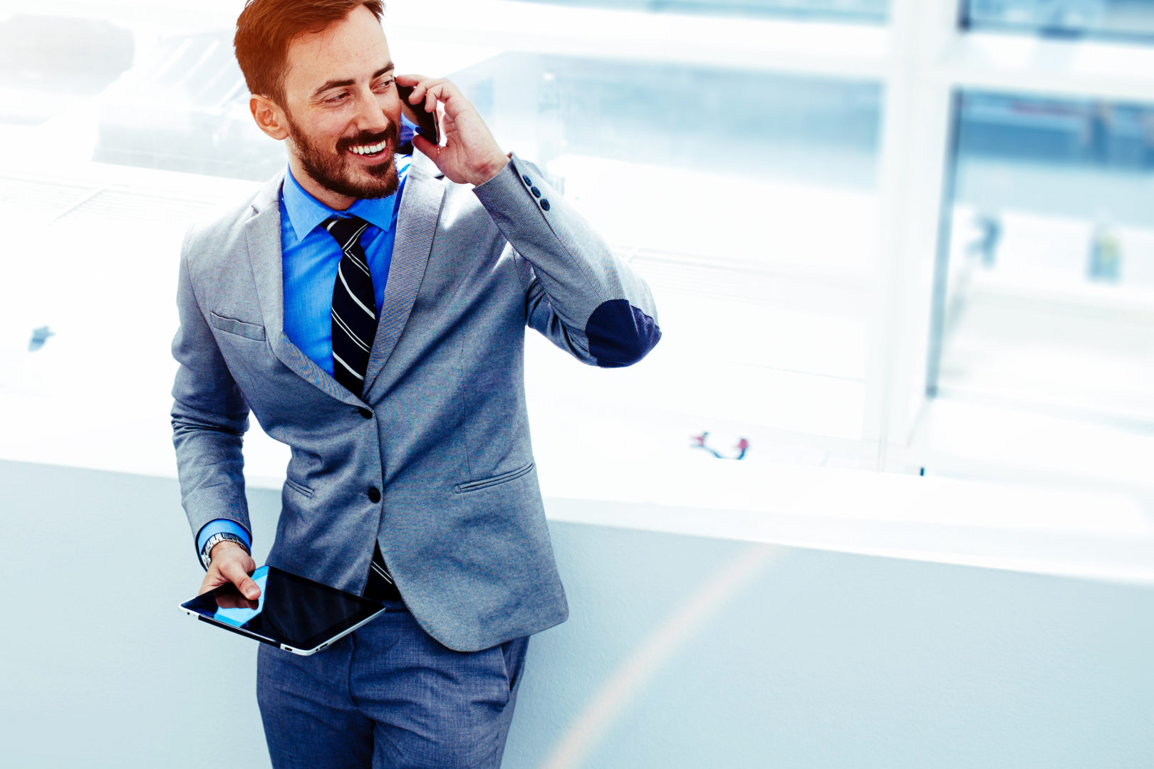 Business in the cloud, man laughing on phone with tablet.